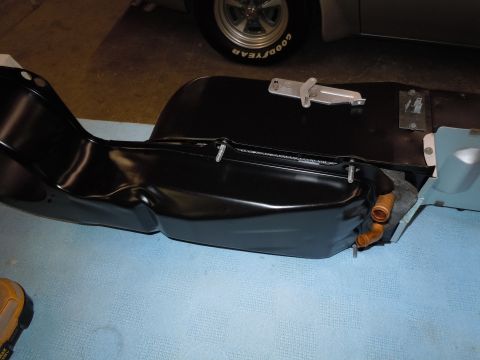 1973 Pontiac Trans Am - A black metal part with copper fittings and a metal latch is shown, with a tire and part of a vehicle in the background.