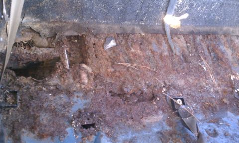 1979 Ford Bronco - The interior floor pan of a vehicle shows extensive rust damage and deterioration.