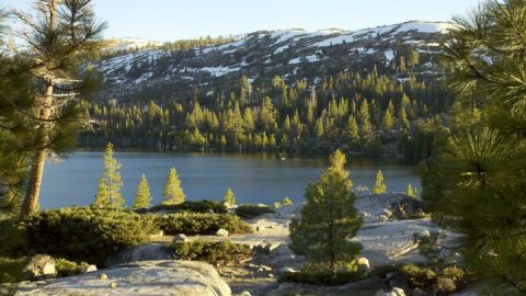 1971 Ford Bronco - Scenic view of a mountain lake with evergreen trees and snow-dusted peaks under a clear sky.