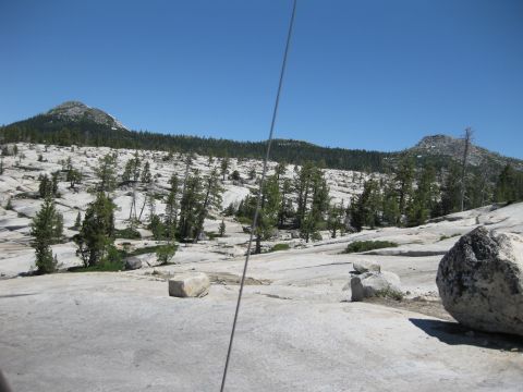1971 Ford Bronco - A wide view of a mountainous, rocky landscape with sparse trees under a bright blue sky.