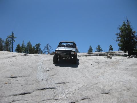 1971 Ford Bronco - A silver SUV navigates a challenging rocky landscape on a sunny day.
