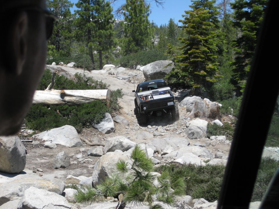 Truck navigating a rocky trail with trees and boulders