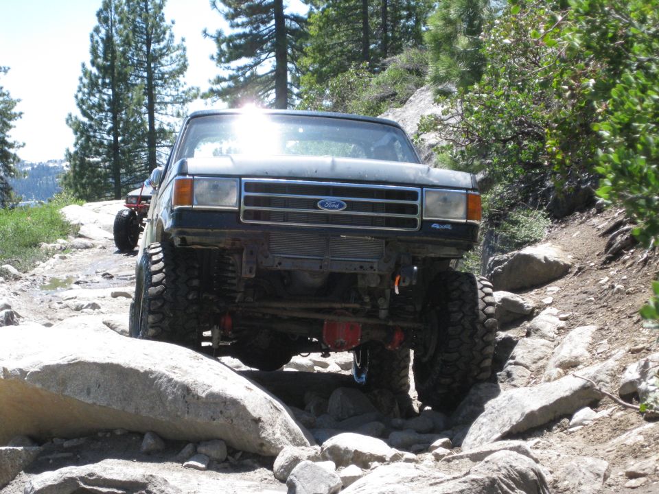Dark gray Ford truck with large tires navigating a rocky trail