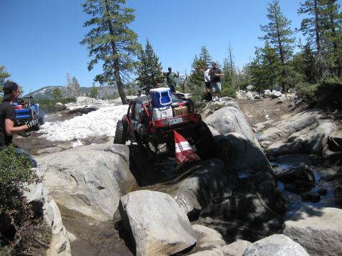 1971 Ford Bronco - Off-road vehicles traverse a challenging rocky path under a clear blue sky.