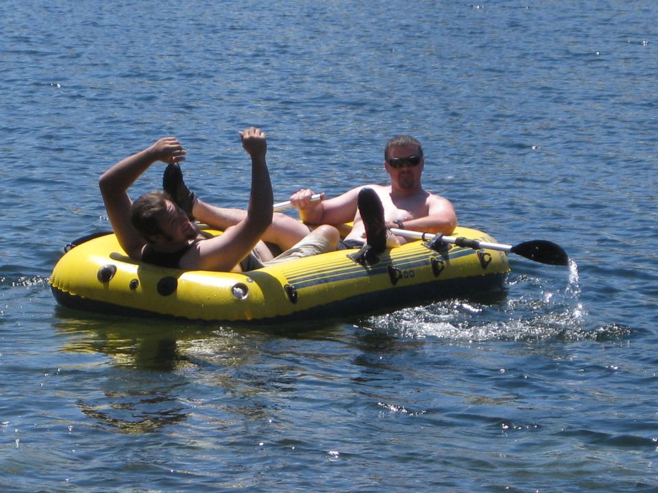 Two men in a yellow inflatable raft paddling on a body of water