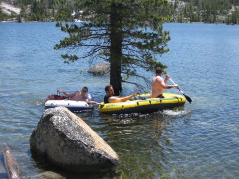 1971 Ford Bronco - People enjoy a sunny day on the water in inflatable boats near a tree and rocks.