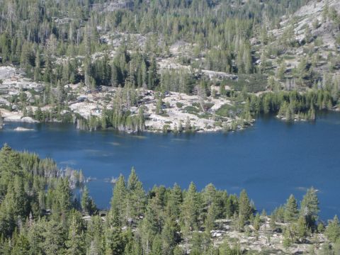1971 Ford Bronco - A scenic view of a deep blue mountain lake with dense evergreen forests and rocky slopes.