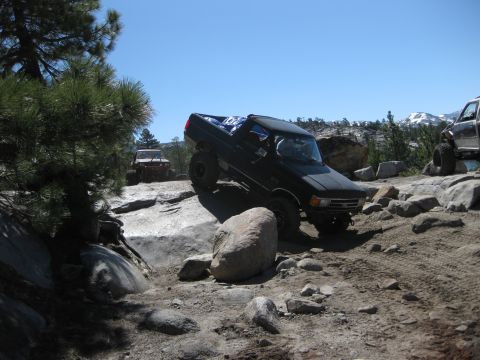 1971 Ford Bronco - Two trucks are off-roading on a sunny day, with mountains in the background.