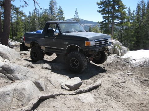 1971 Ford Bronco - This lifted Ford Bronco navigates a challenging rocky terrain under a clear blue sky.