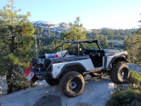 1971 Ford Bronco - Modified 1971 Ford Bronco parked on rocky terrain with a snowy mountain backdrop.