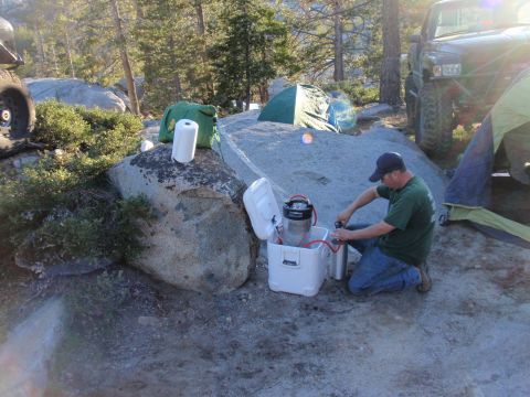 1971 Ford Bronco - A man prepares a keg at a campsite next to an off-road vehicle and tents.