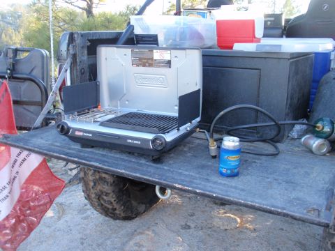 1971 Ford Bronco - A Coleman grill and propane tank are set up in the bed of a pickup truck, ready for use outdoors.
