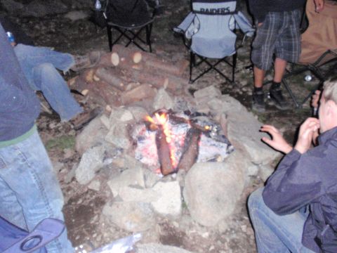 1971 Ford Bronco - Friends gather around a crackling campfire, enjoying the outdoors with camping chairs set up.