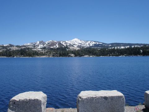 1971 Ford Bronco - Scenic view of a lake with snow-covered mountains in the background under a clear blue sky.