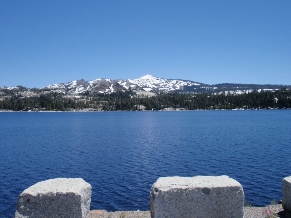 Blue lake with snow on distant mountains and trees