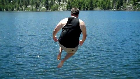 1971 Ford Bronco - Man jumps into a lake on a sunny day. Supermotors.net logo is visible.