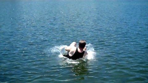 1971 Ford Bronco - person swims in a deep blue lake, splashing water on a sunny day.