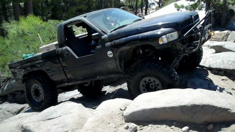 1971 Ford Bronco - This modified black pickup truck navigates a challenging rocky trail, its off-road capabilities.