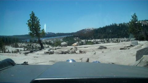 1971 Ford Bronco - View from inside a vehicle traveling through a rocky, natural landscape under a clear blue sky.