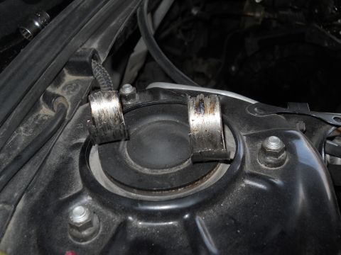 2006 Ford E350 - Close-up of suspension strut mount hardware, showing two metal clamps.