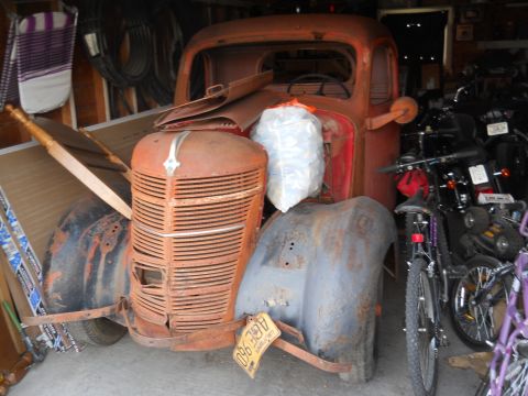2006 Ford E350 - An old, weathered truck sits in a cluttered garage, surrounded by motorcycles and bicycles.