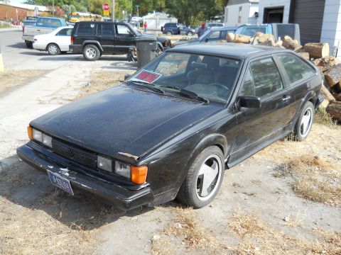 2006 Ford E350 - A black Volkswagen Scirocco is parked on a dirt lot, with a 'For Sale' sign visible on the windshield.