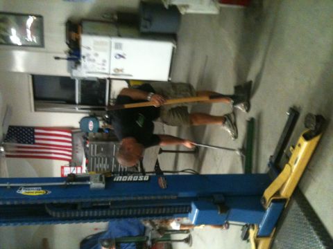 1966 Ford Bronco - Garage scene with a man and a car lift. The image includes an American flag on the wall.