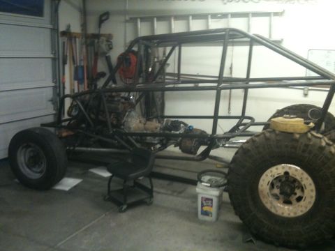 1966 Ford Bronco - A custom buggy frame, mid-build, is shown in a garage with its engine and large off-road tires visible.