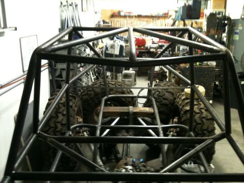 1966 Ford Bronco - Roll cage and large tires of a custom off-road buggy in a workshop.