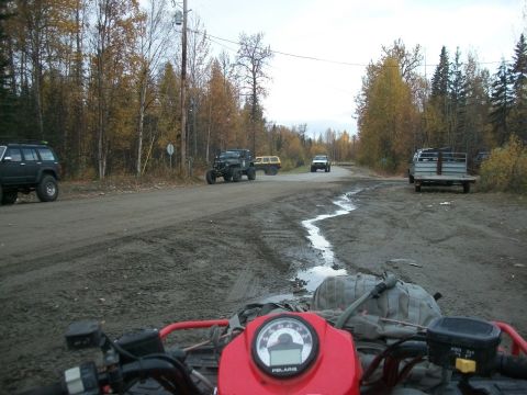 1979 Ford Bronco - View from an ATV dashboard on a muddy road with multiple off-road vehicles in the background.