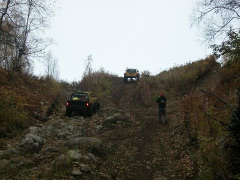 1979 Ford Bronco - Two off-road vehicles navigate a challenging, rocky incline on a cloudy day.