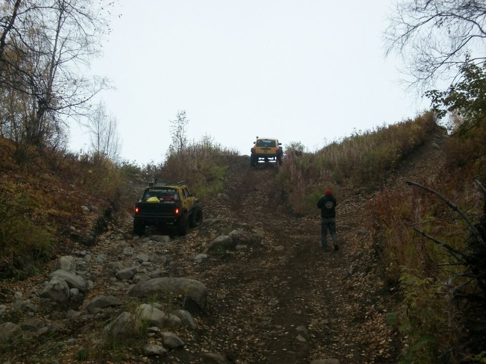 Yellow off-road SUV climbing a rocky hill, another vehicle behind it