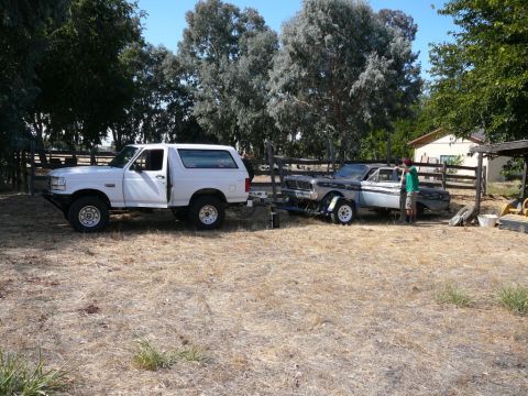 1988 Ford Bronco - A white 1988 Ford Bronco is seen towing a trailer carrying a classic car.