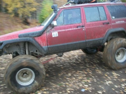 1979 Ford Bronco - This red SUV, equipped for off-roading with a snorkel and oversized tires, navigates a leaf-strewn path.