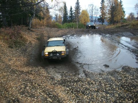 1979 Ford Bronco - Two SUVs tackle a challenging muddy off-road course during autumn.