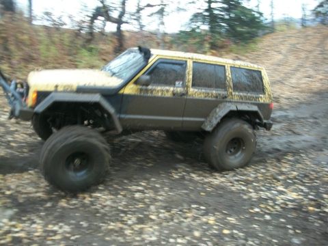 1979 Ford Bronco - This heavily modified Jeep Cherokee XJ is shown navigating a muddy, off-road trail.