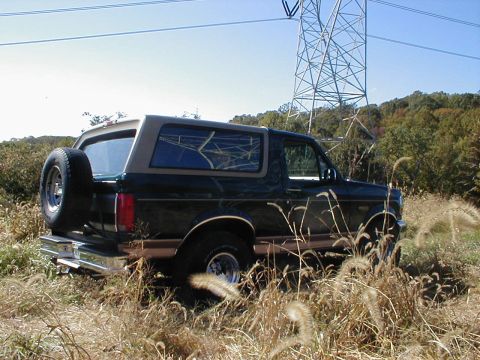 1995 Ford Bronco - A Ford Bronco is parked in a grassy field with a large power line tower in the background.