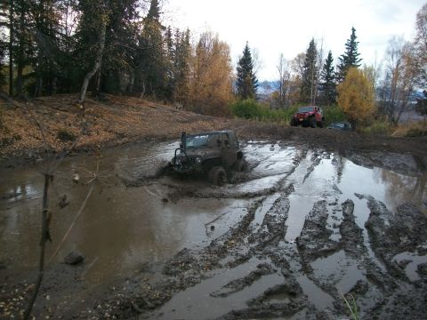 1979 Ford Bronco - Off-road vehicles navigate a challenging muddy terrain during an autumn day.
