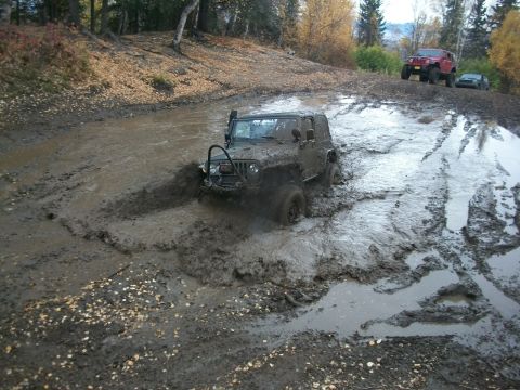1979 Ford Bronco - Off-road vehicles navigate a challenging muddy terrain during an autumn day.