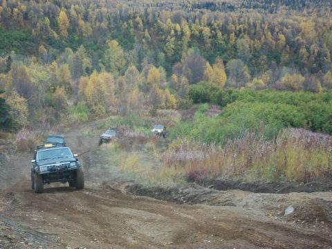1979 Ford Bronco - Multiple off-road vehicles navigate a dirt trail amidst a backdrop of colorful autumn trees.