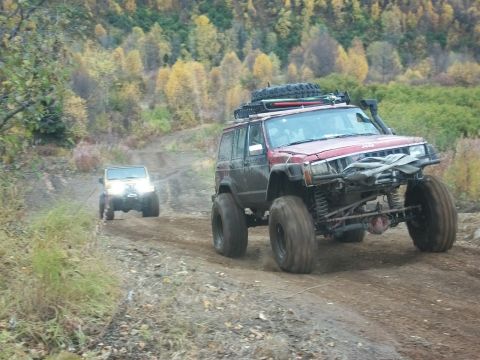1979 Ford Bronco - Two modified Jeeps navigate a dirt trail through autumn foliage.