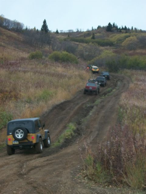 1979 Ford Bronco - A convoy of SUVs navigates a challenging dirt path in a rural, autumnal setting.
