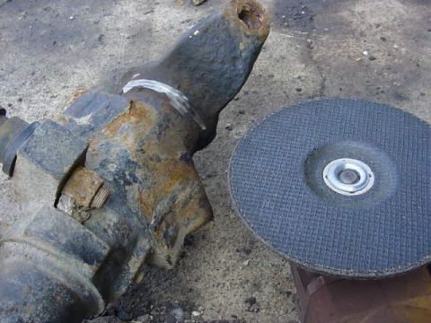 1992 Ford Bronco - A heavily rusted metal part sits beside a grinding disc, suggesting repair or fabrication work.