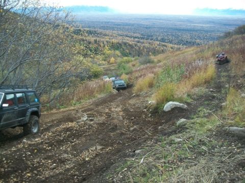 1979 Ford Bronco - Multiple off-road vehicles traverse a challenging dirt path amidst a scenic, autumnal landscape.