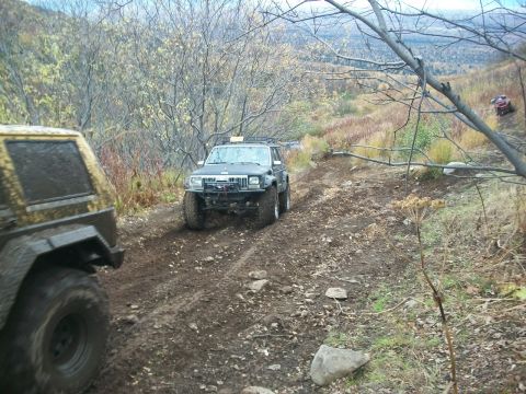 1979 Ford Bronco - Two SUVs navigate a challenging muddy trail during an off-road excursion.