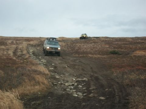 1979 Ford Bronco - Two SUVs navigate a challenging off-road trail under an overcast sky.