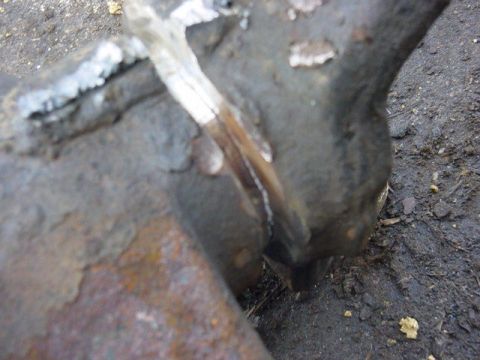 1992 Ford Bronco - Close-up of a rusty metal part with visible welds, resting on the ground.
