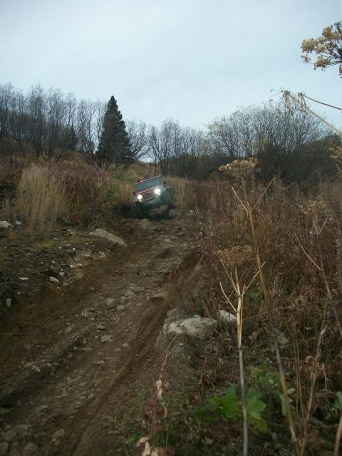 1979 Ford Bronco - An off-road vehicle navigates a challenging rocky incline under an overcast sky.