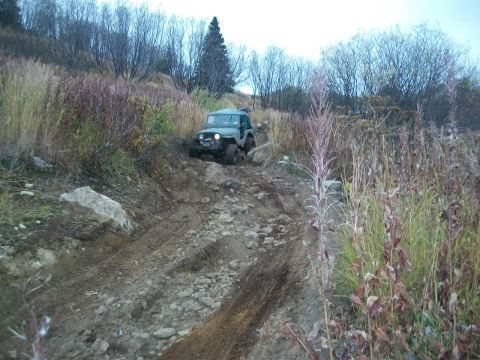1979 Ford Bronco - Jeep CJ-7 navigates a challenging off-road trail during the autumn season.