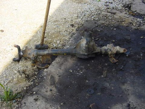1992 Ford Bronco - A disassembled front axle assembly lies on the ground, showing signs of wear and tear.